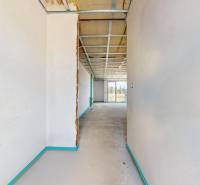 A hallway in a family house with an unfinished ceiling and a view of nature.