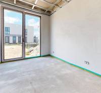 The interior of a family house with balcony doors, view of the yard, in the state of rough construction.