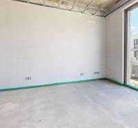 A room in a family house with a concrete floor and a large window.