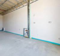 Unplastered room with installation in a family house, exposed ceiling and doors to the terrace.