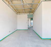 An empty interior with a concrete floor and an unfinished ceiling in a family house.