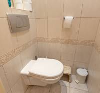 A toilet with light tiles and folding doors in a 4-room apartment.