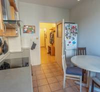 A kitchen in a 4-room apartment with a table, chairs, a refrigerator, and a stove.