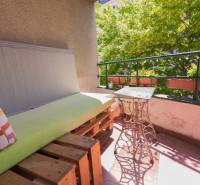 A balcony with wooden pallets and a metal table in a 4-room apartment.