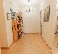 A hallway in a 4-room apartment with shoe shelves and a wooden decor floor.