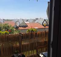 A balcony in a 3-room apartment with rattan furniture and a view of the rooftops.