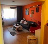 Living room of a 3-room apartment with an orange wall, a sofa, and a coffee table.