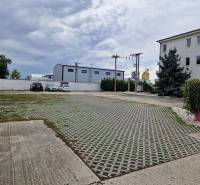Parking lot on Šamorínska Street near warehouses and halls, marked with a real estate agency sign.