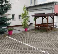 Mansion with paving, wooden seating, and plants in pink pots on Šamorínska Street.
