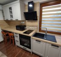 A kitchen in a studio apartment with wooden elements, equipped with an oven, sink, and appliances.