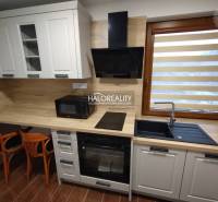 Kitchen area in a studio apartment with wooden furniture and appliances.