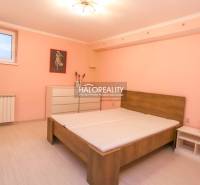 A bedroom with a bed in a 2-room apartment with a spacious dresser and a pastel pink wall.