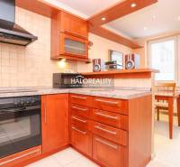 A kitchen in a 2-room apartment with a wooden kitchen unit, stove, extractor hood, and dining area.