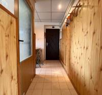 Wooden paneling in the hallway of a 2-room apartment, light tiles, folding chairs.