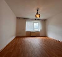 A room with a wooden floor and pendant lighting in a 2-room apartment.