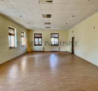 Spacious room in a building with wooden flooring and multiple windows.