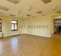 A spacious room with wooden flooring and multiple windows.