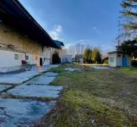 Production premises on Hlavná Street in Kovarce with greenery and buildings in the yard.