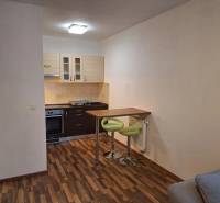 A kitchen corner with a bar counter and wooden flooring in a two-room apartment.