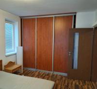 Bedroom in a 2-room apartment with wooden flooring, a wardrobe, and a bed.