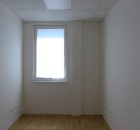 Room with a window, light walls, and floor in warehouse and hall spaces.