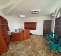 Offices with wooden furniture and green chairs, tiles, arched window.