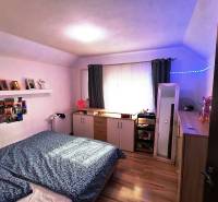Bedroom in a family house with wooden flooring, decorations, and storage space.
