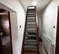 Interior of a family house with a staircase, next to a radiator and entrance to the bathroom.