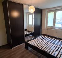 Bedroom in a 2-room apartment with a dark wardrobe, bed, and window.
