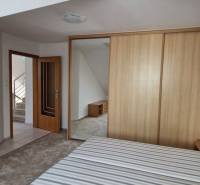 Bedroom in a family house with a wooden wardrobe and open doors to the hallway.