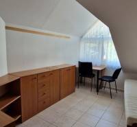 A room in a family house with storage space, two chairs, and a window with curtains.
