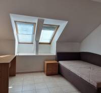 Attic room in a family house with two skylights, a bed, and a desk.