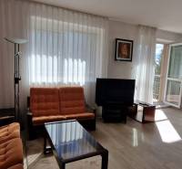 Living room with orange furniture, a television, and large windows, Family house.