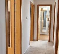 A hallway in a family house with doors, tiles, and a view into the bathroom.