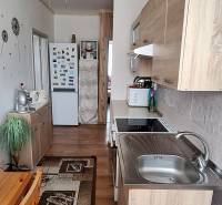A kitchen in a 3-room apartment with wooden furniture and a ceiling fan.