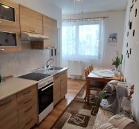 A kitchen in a 3-room apartment with wooden cabinets and a dining table, light decoration.