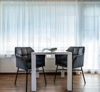Dining table with chairs in a 2-room apartment, light curtains, wooden floor.