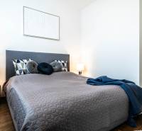 A bedroom in a two-room apartment with a comfortable bed, a table lamp, and decorative pillows.