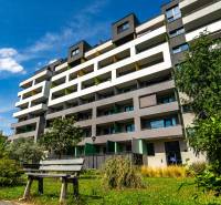 The building on Strojárenská in Košice-Staré Mesto, surrounded by greenery, with a park bench.