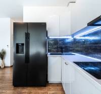 A kitchen in a 2-room apartment with a black refrigerator, modern cabinetry, and wooden flooring.
