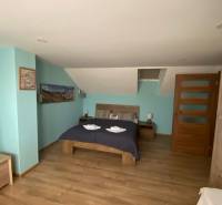 Bedroom in a family house with a double bed, wooden floor, and decorations.