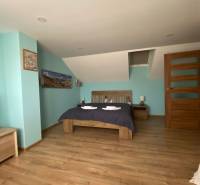 Family house: Sloped ceiling, double bed, wooden floor, blue wall, and nightstands.