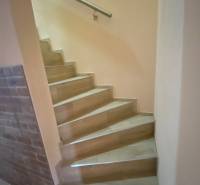 A staircase in a family house with a brick wall and a steel railing.