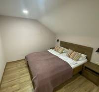 Bedroom in a family house with wooden flooring, a double bed, and a nightstand.