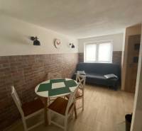 A room with a brick wall, a table, chairs, and a sofa in a family house.