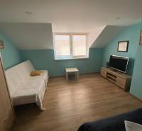 A room in a family house with a sofa, television, and wooden floor.