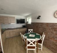 A kitchen with a dining table and brick cladding in a family house.