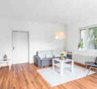Living room in a two-room apartment with wooden flooring, a sofa, and stylish lighting.
