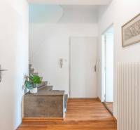 A hallway with a wooden floor, staircase, picture, and radiator in a 2-room apartment.