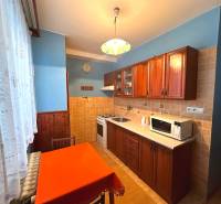 A kitchen in a 3-room apartment with wooden cabinets and a dining table.